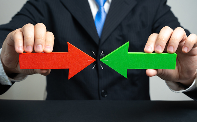 [Translate to English:] Mann mit Pfeilen rot und grün in der Hand, die sich auf einander zu bewegen.